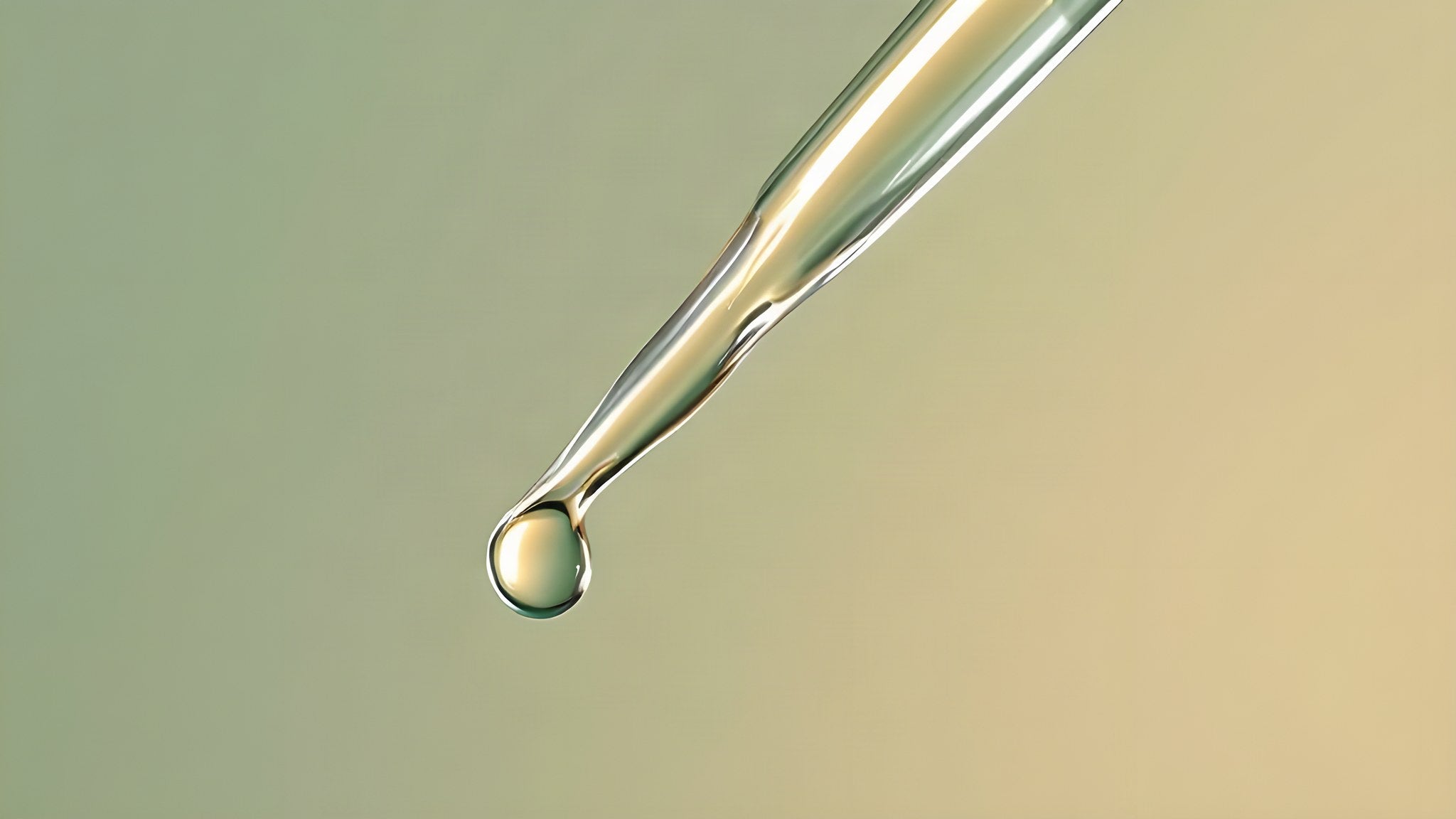 The glass tip of a dropper, a single clear drop forming