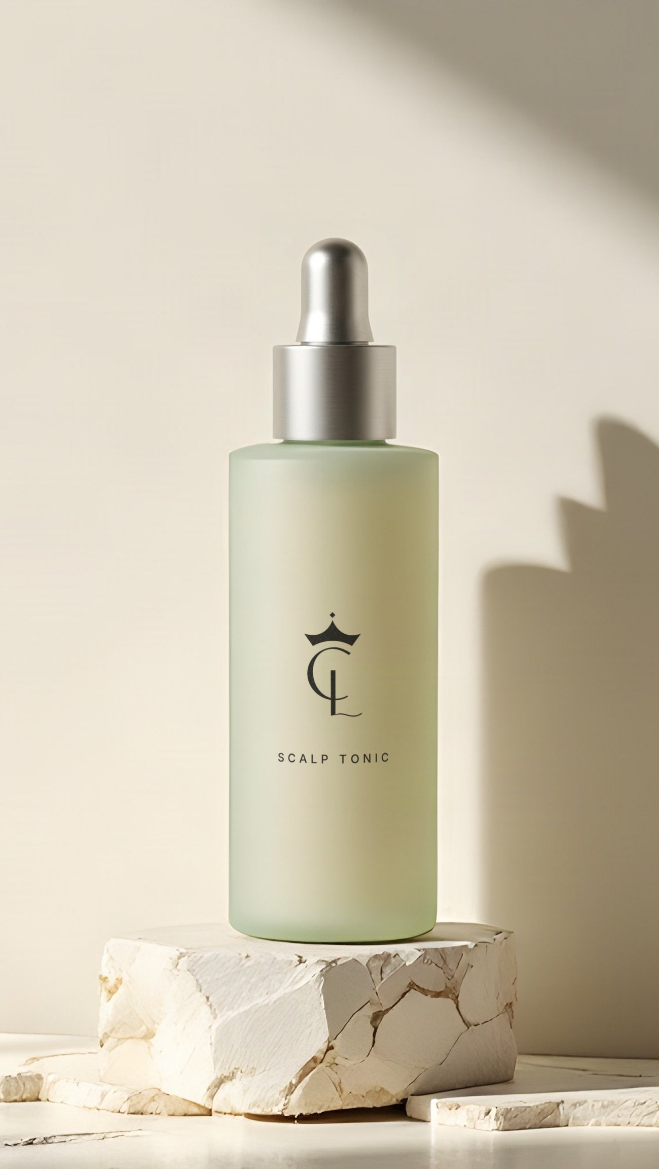 The Scalp Tonic, a slim frosted sage dropper bottle with a matte silver dropper, on a block of rough travertine in warm side light.