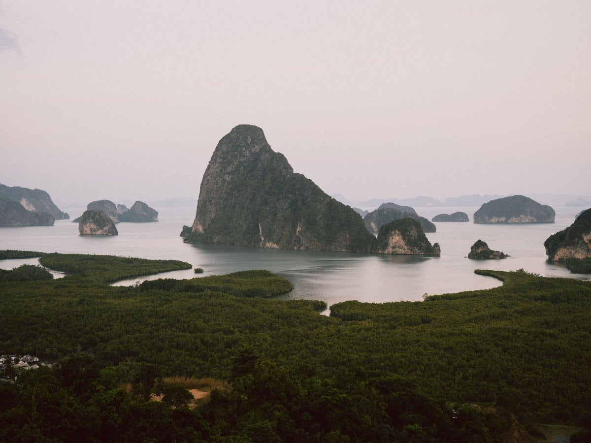 Limestone islands rising out of soft haze above the water in Phang Nga Bay
