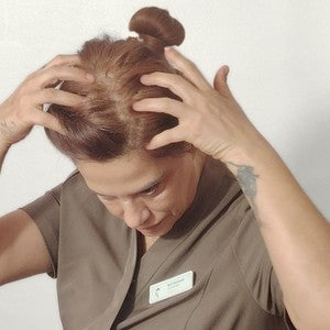 Revi presses the drops into her scalp with her fingertips
